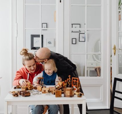 A loving family enjoying playtime with wooden toys in a cozy indoor setting.
